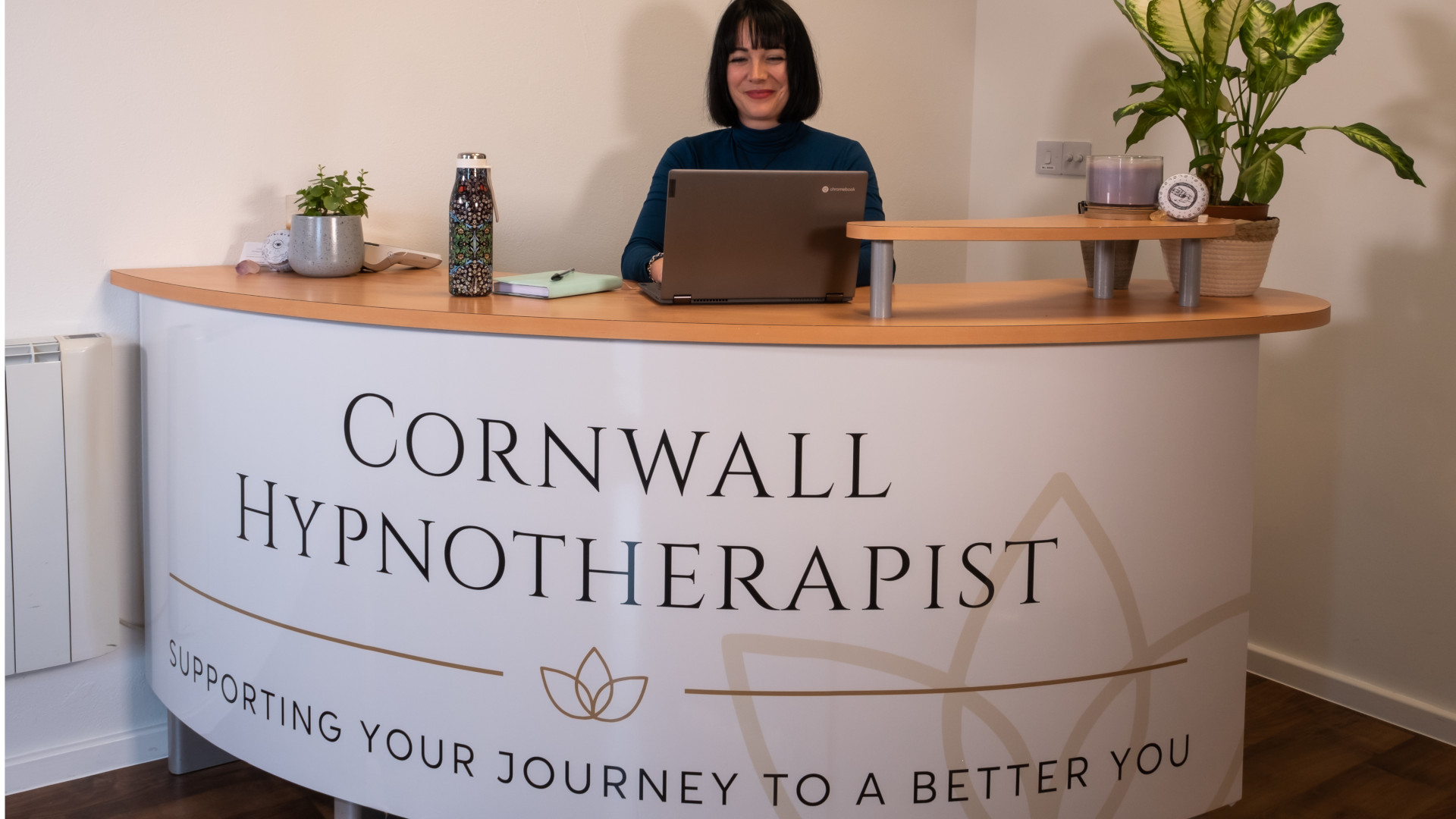Daisy standing behind her reception desk and working on a laptop